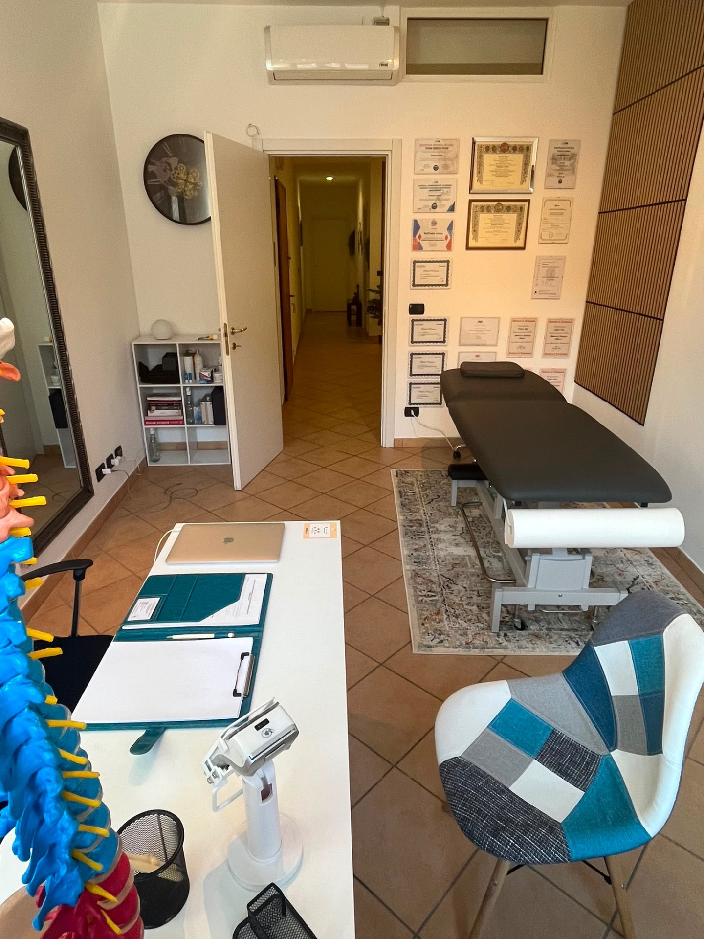 Interno dello Studio Synapsi ad Asti: sala di terapia manuale con parete degli attestati